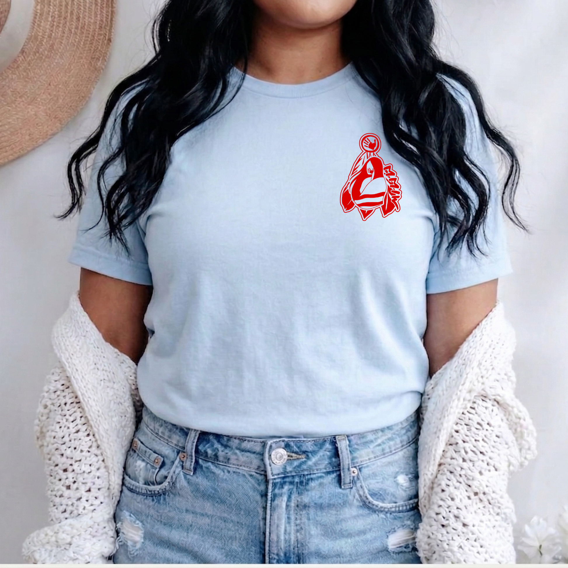 Person wearing a light blue t-shirt with a red graphic design, paired with jeans and a white cardigan. MMIW shirt, MMIW woman in feathers, pocket design shirt, Indigenous awareness tee, Missing and Murdered Indigenous Women, Indigenous graphic tee, unisex t shirt, activism shirt, Indigenous justice, feather shirt, awareness apparel, Native shirt, statement tee, solidarity shirt, Indigenous owned brand
