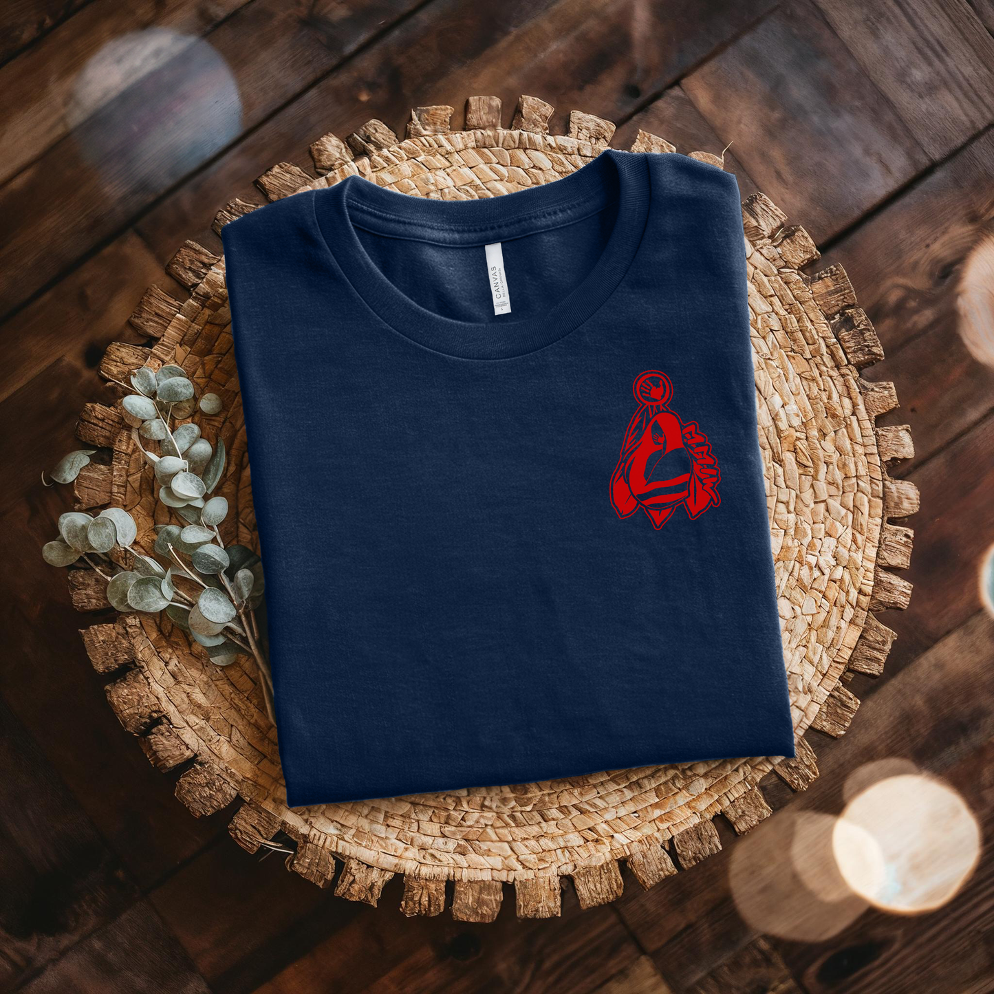 Folded navy blue t-shirt with a red logo on a woven mat. MMIW shirt, MMIW woman in feathers, pocket design shirt, Indigenous awareness tee, Missing and Murdered Indigenous Women, Indigenous graphic tee, unisex t shirt, activism shirt, Indigenous justice, feather shirt, awareness apparel, Native shirt, statement tee, solidarity shirt, Indigenous owned brand