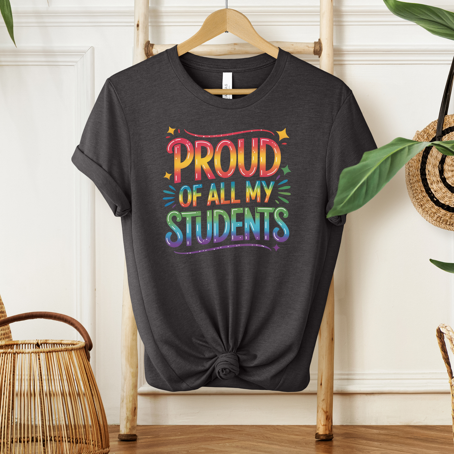 Black t-shirt with colorful text 'PROUD OF ALL MY STUDENTS' on a wooden hanger. teacher pride shirt, inclusive teacher shirt, LGBTQ ally teacher gift, pride month shirt, supportive teacher apparel, equality shirt for educators, school pride clothing, safe space shirt, diversity and inclusion tee, teacher appreciation gift, back to school pride shirt, unisex teacher shirt, classroom pride outfit, LGBTQ pride clothing, positive message shirt