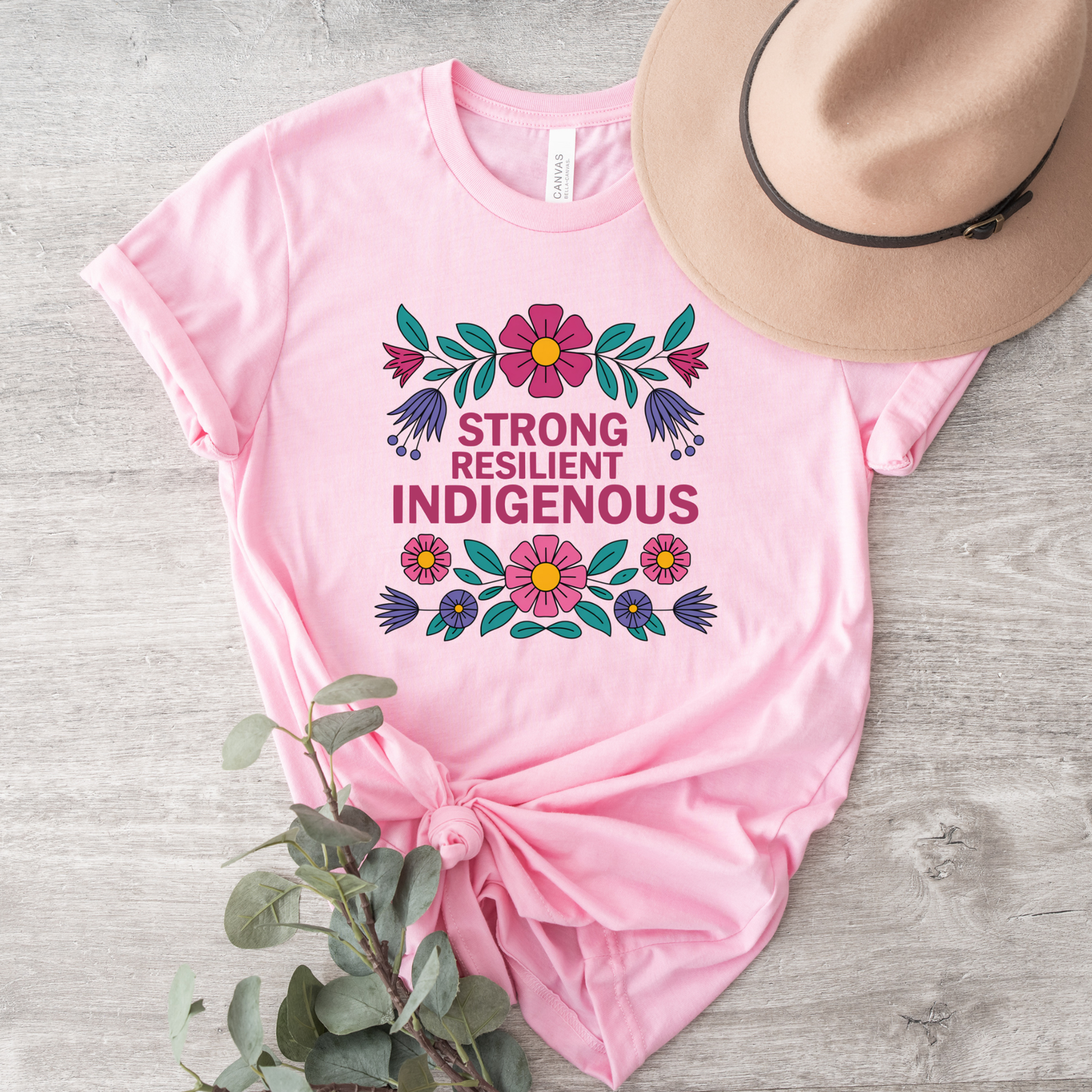 pink t-shirt with colorful floral design that says strong resilient indigenous, strong resilient indigenous t-shirt, indigenous floral tee, resilience graphic shirt, indigenous empowerment apparel, floral indigenous design, unisex indigenous shirt, sahdeh spruce clothing, indigenous pride t-shirt, native resilience tee, indigenous artist design, cultural strength shirt, heritage graphic apparel