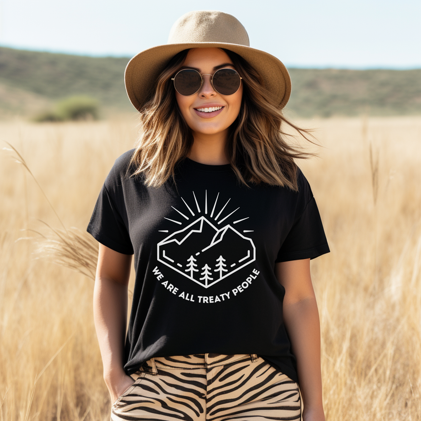 Woman wearing a black t-shirt with a graphic and text, standing in a field. We Are All Treaty People, treaty shirt, Indigenous treaty awareness, Indigenous t shirt, unisex graphic tee, reconciliation shirt, Indigenous rights, awareness tee, activist shirt, Native apparel, solidarity shirt, truth and reconciliation, statement tee, Indigenous owned brand, educational shirt