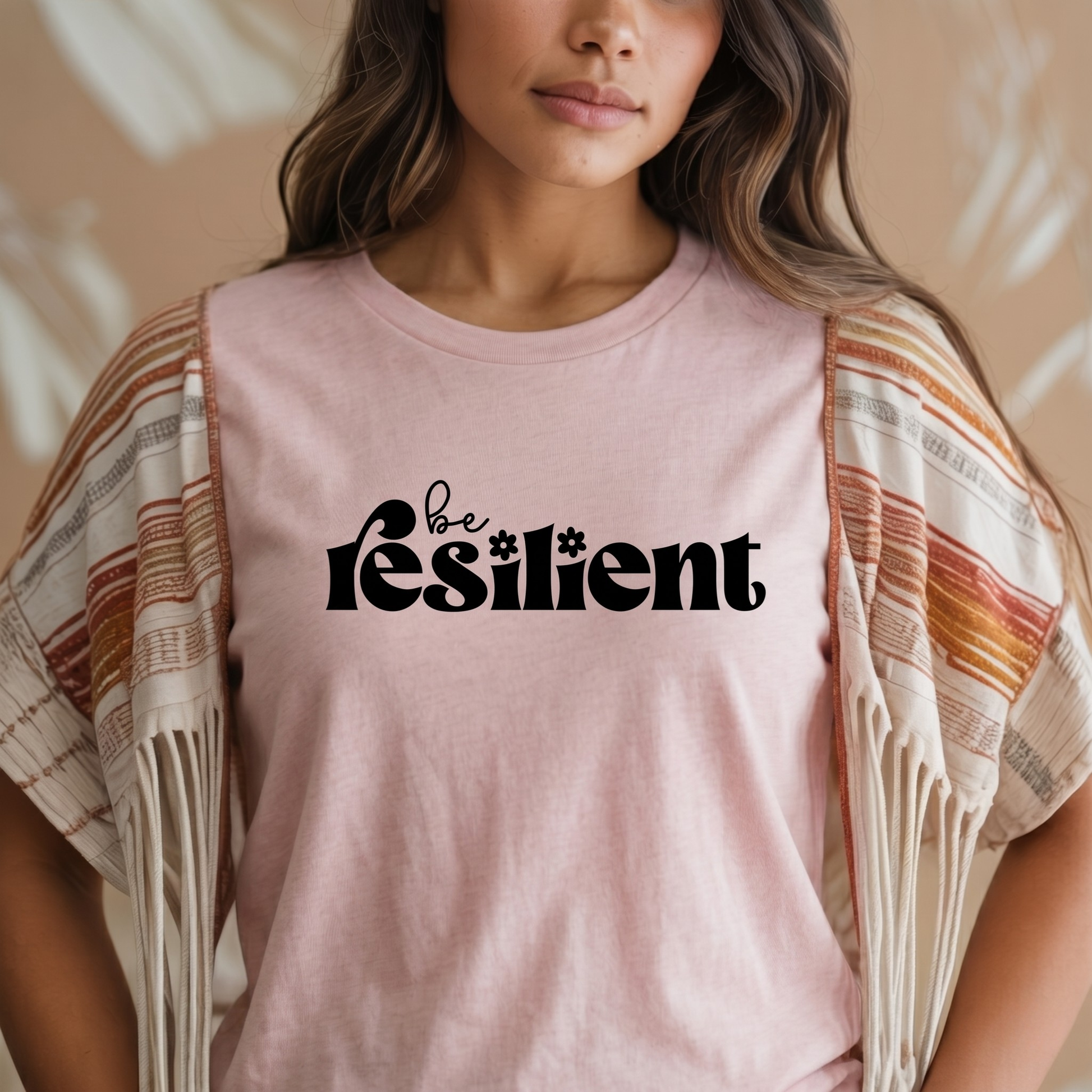 shirt with bold black retro typography that reads "Be Resilient" with subtle floral accents, symbolizing strength, perseverance, and personal growth. be resilient shirt, resilience t-shirt, motivational graphic tee, inspirational apparel, positive affirmation shirt, empowerment clothing, strength and perseverance shirt, mental wellness apparel, self growth clothing, motivational gift ideas, encouragement shirt, inspirational quote tee, positive mindset clothing, resilience gift, uplifting graphic shirt
