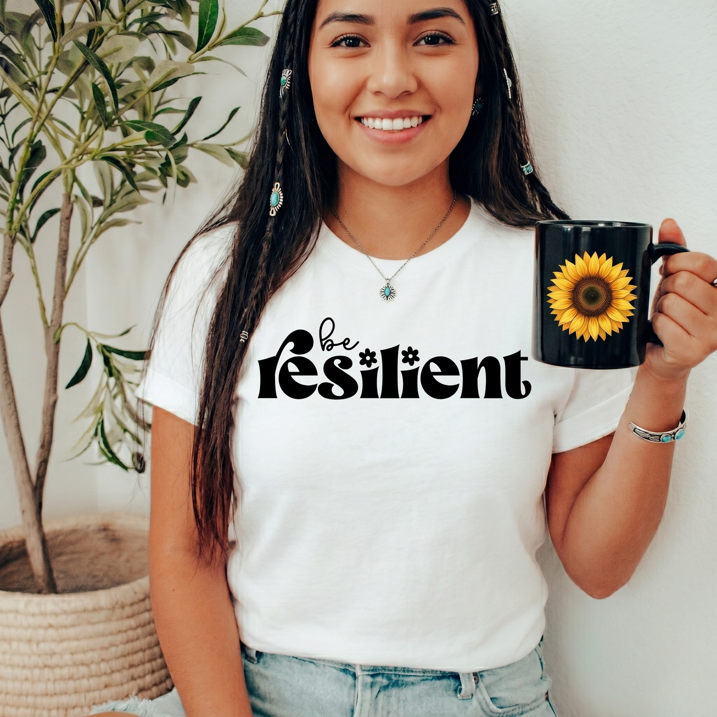 shirt with bold black retro typography that reads "Be Resilient" with subtle floral accents, symbolizing strength, perseverance, and personal growth. be resilient shirt, resilience t-shirt, motivational graphic tee, inspirational apparel, positive affirmation shirt, empowerment clothing, strength and perseverance shirt, mental wellness apparel, self growth clothing, motivational gift ideas, encouragement shirt, inspirational quote tee, positive mindset clothing, resilience gift, uplifting graphic shirt
