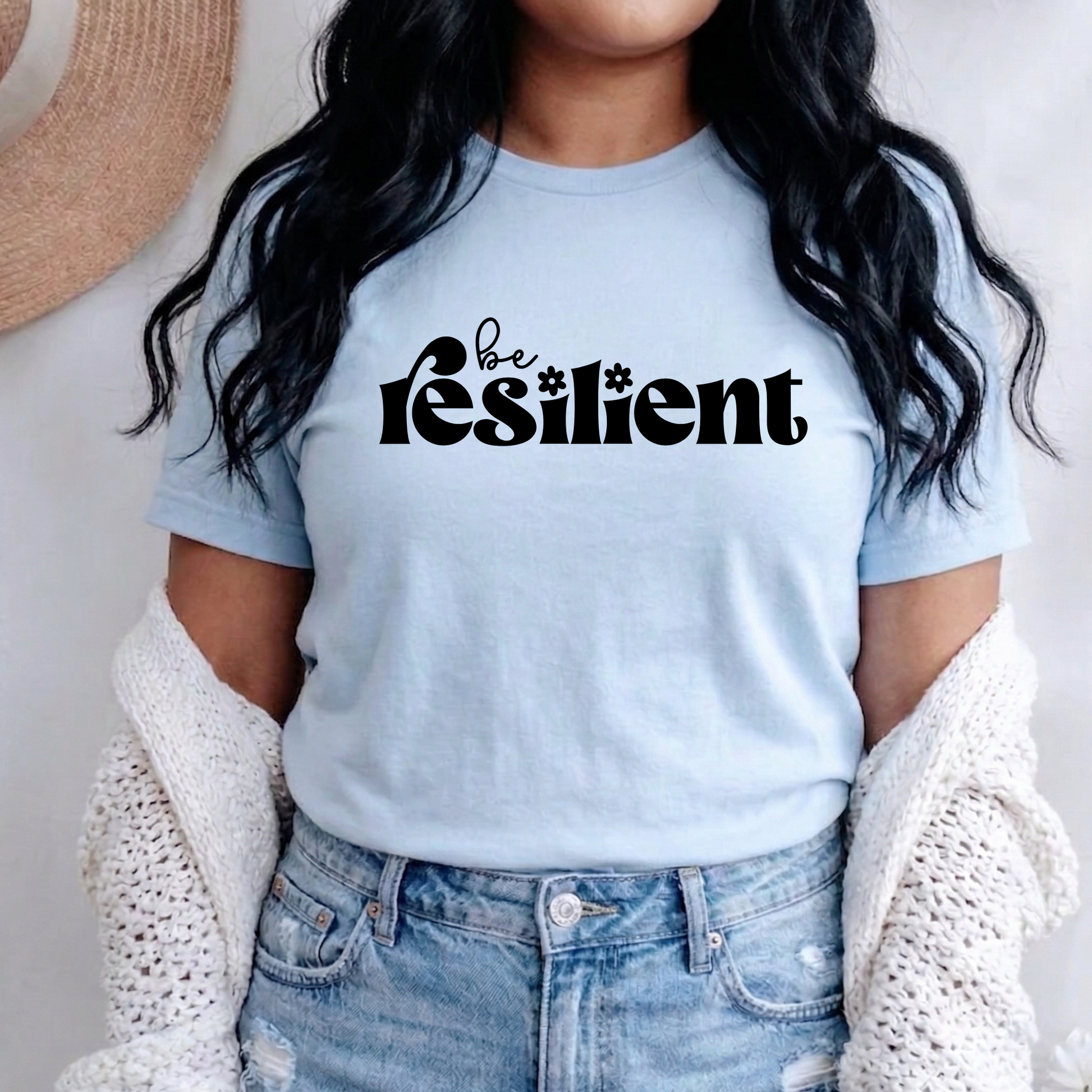 shirt with bold black retro typography that reads "Be Resilient" with subtle floral accents, symbolizing strength, perseverance, and personal growth. be resilient shirt, resilience t-shirt, motivational graphic tee, inspirational apparel, positive affirmation shirt, empowerment clothing, strength and perseverance shirt, mental wellness apparel, self growth clothing, motivational gift ideas, encouragement shirt, inspirational quote tee, positive mindset clothing, resilience gift, uplifting graphic shirt