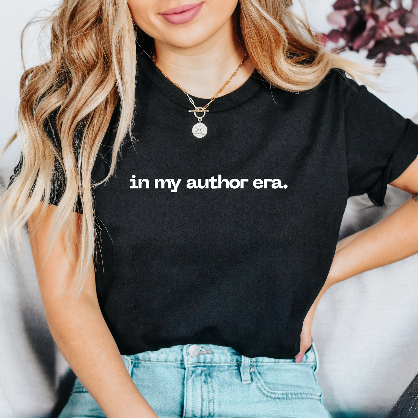Person wearing a black t-shirt with 'in my author era.' text, sitting on a couch. in my author era shirt, writer shirt, author tee, writing shirt, nanowrimo shirt, book author apparel, novelist shirt, writer gift shirt, author era tee, creative writer clothing, book launch shirt, writing community tee, aspiring author shirt, fiction writer apparel, manuscript shirt
