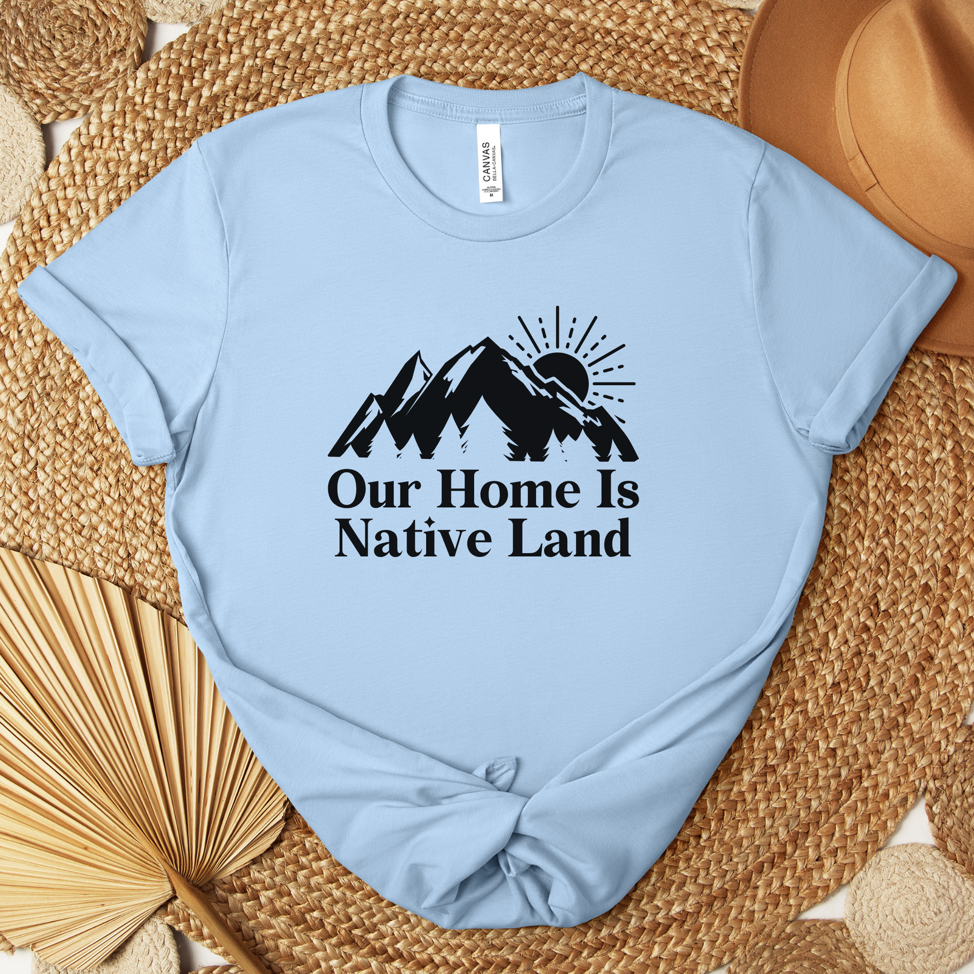 Our Home Is Native Land shirt with white mountain and sunrise graphic on a unisex t-shirt. our home is native land shirt, indigenous pride tee, native pride shirt, indigenous apparel, unisex graphic tee, land acknowledgment shirt, indigenous awareness shirt, statement tee, mountain sunrise shirt, everyday wear shirt, community event shirt, indigenous clothing, native land shirt, meaningful graphic tee, cultural pride shirt