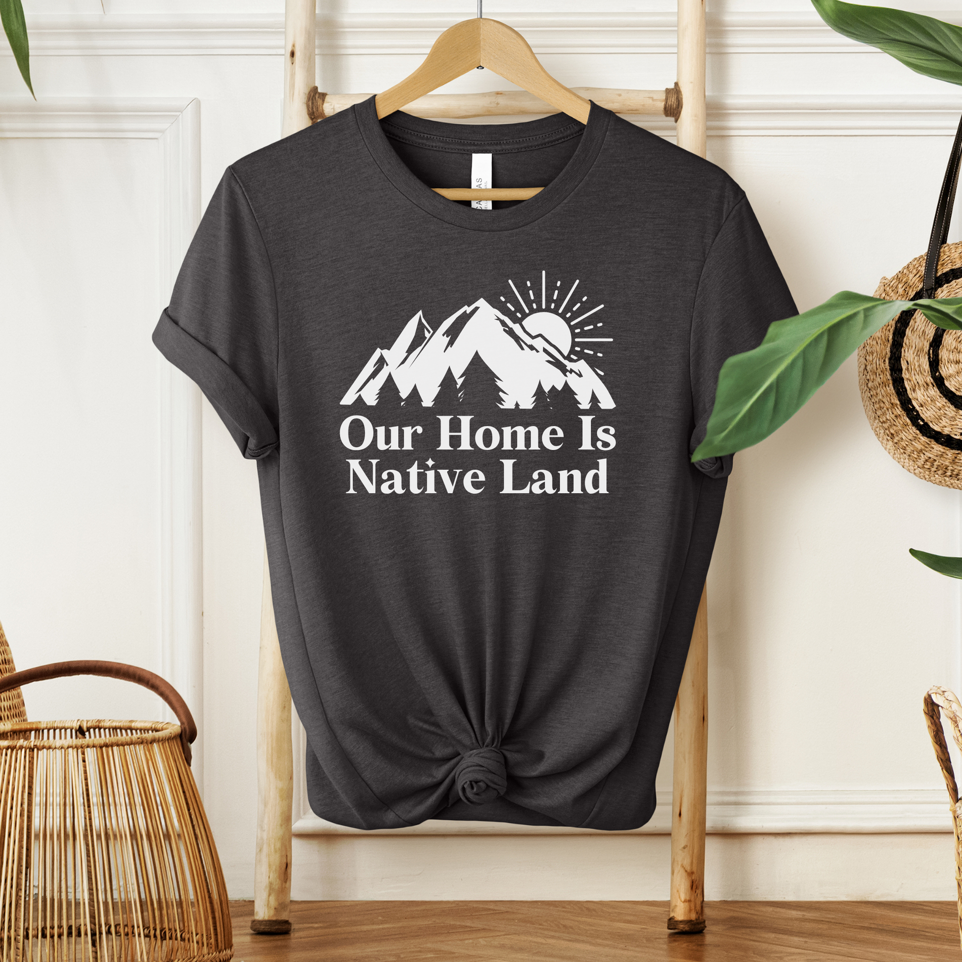 Our Home Is Native Land shirt with white mountain and sunrise graphic on a unisex t-shirt. our home is native land shirt, indigenous pride tee, native pride shirt, indigenous apparel, unisex graphic tee, land acknowledgment shirt, indigenous awareness shirt, statement tee, mountain sunrise shirt, everyday wear shirt, community event shirt, indigenous clothing, native land shirt, meaningful graphic tee, cultural pride shirt