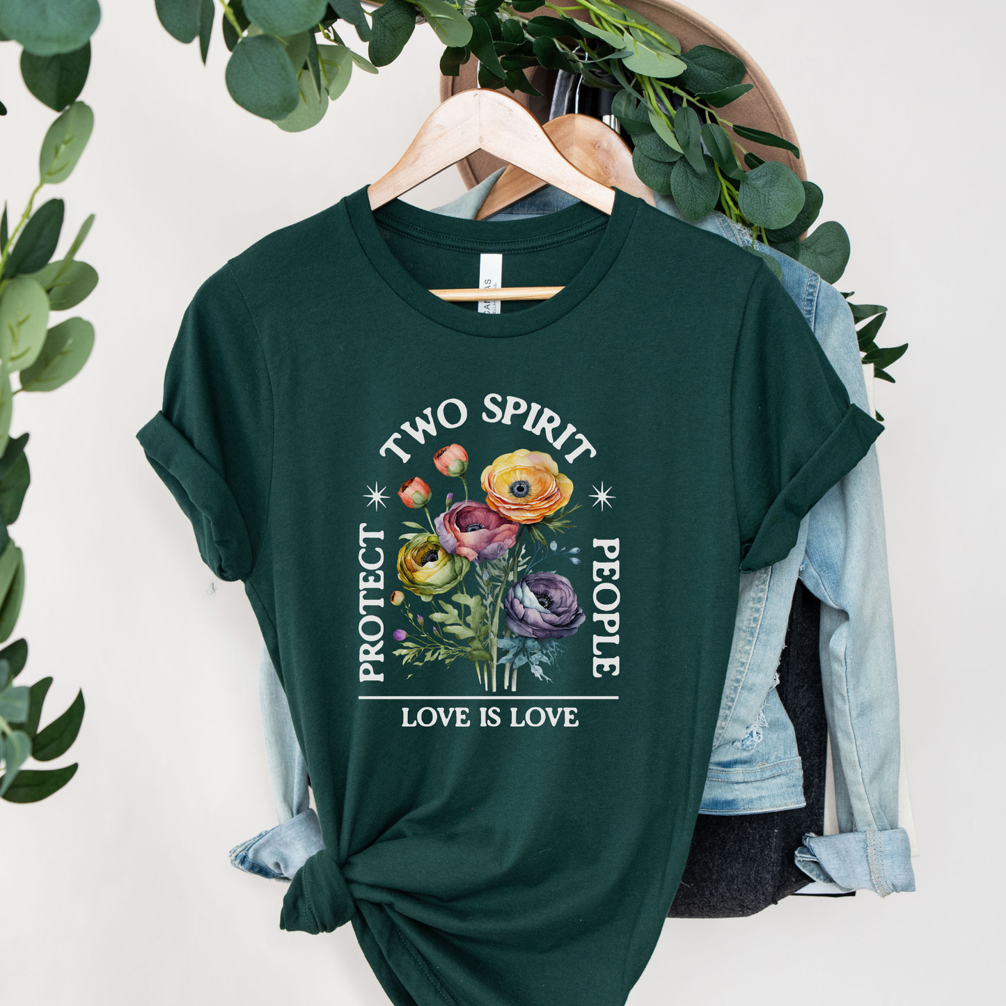  protect two spirit people shirt, love is love two spirit tee, indigenous lgbtq shirt, two spirit pride t-shirt, indigenous pride apparel, lgbtq indigenous tee, two spirit advocacy shirt, love is love unisex tee, 2s pride shirt, indigenous lgbtq clothing, two spirit protection tee, queer indigenous apparelGreen t-shirt with floral design and text on a hanger with greenery in the background