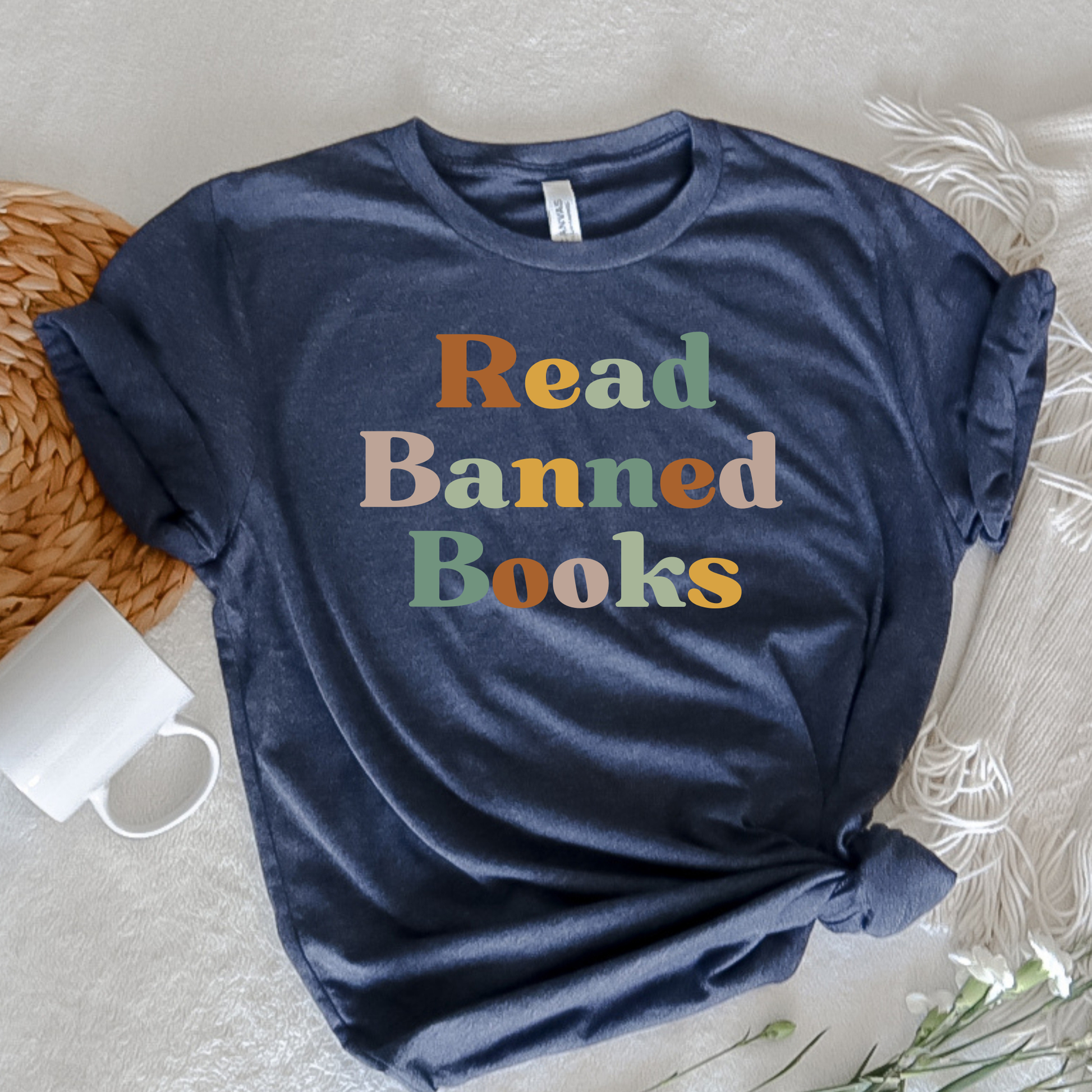 Navy blue t-shirt with 'Read Banned Books' text in multicolor on a light surface. read banned books shirt, banned books tee, book lover shirt, librarian shirt, teacher book shirt, freedom to read shirt, literary shirt, bookish apparel, reading shirt, library activism shirt, anti censorship shirt, intellectual freedom tee, book club shirt, educational shirt, reader gift shirt