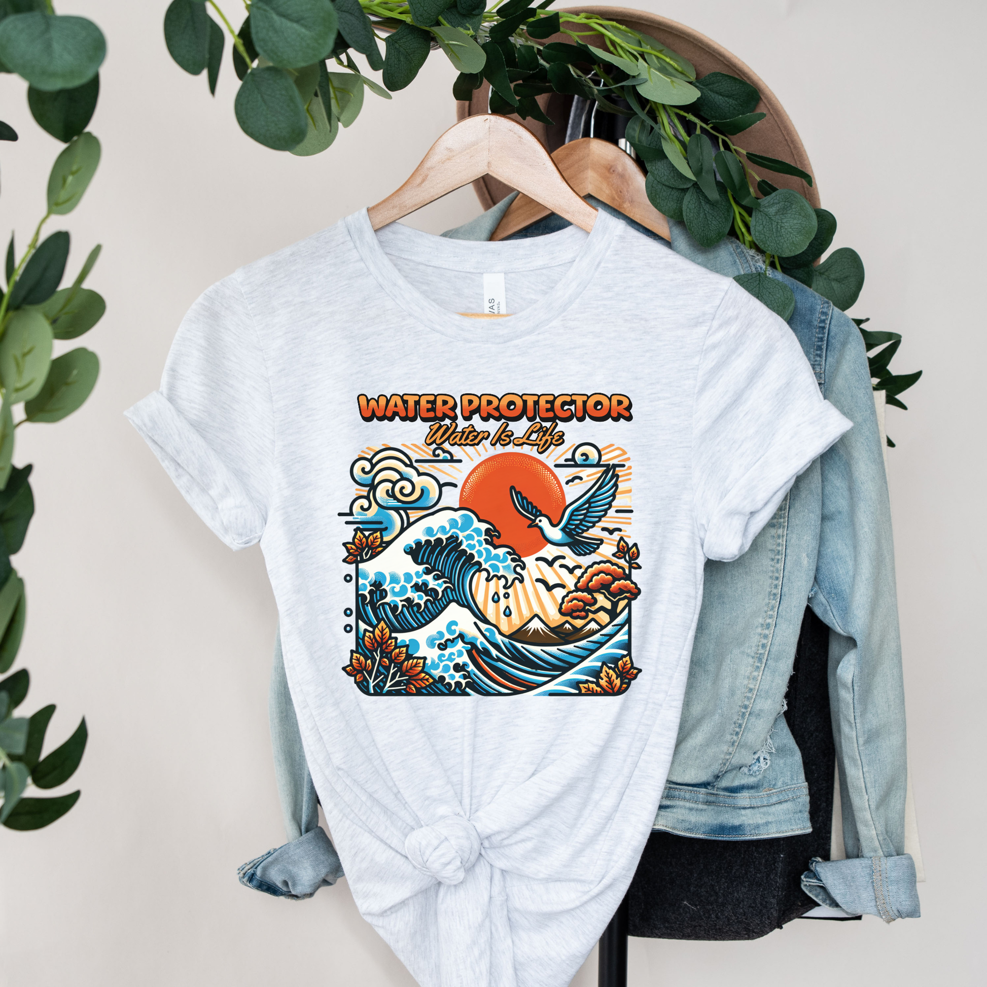 t-shirt featuring a colorful "Water Protector – Water Is Life" graphic with ocean waves, birds, mountains, autumn leaves, and a vibrant sunset, symbolizing environmental stewardship and respect for water. water protector shirt, water is life t-shirt, indigenous environmental apparel, protect our water shirt, environmental awareness tee, sustainability shirt, indigenous advocacy clothing, water stewardship apparel, activist graphic tee, nature lover t-shirt, earth day apparel, eco conscious clothing, environ